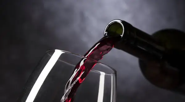 Un vin rouge est versé dans un verre. Parfait pour accompagner un poulet basquaise.