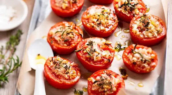 Tomates provençales garnies d'herbes et de fromage, rôties sur une plaque. Un délice méditerranéen.