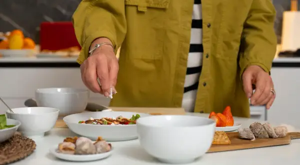 Une personne prépare une salade. Si vous cherchez par quoi remplacer du vin blanc dans une recette, pensez à des ingrédients frais et savoureux comme ceux présentés.