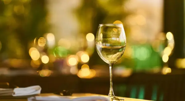 Verre de vin blanc sur une table, ambiance feutrée. La durée conservation vin blanc fermé est une question clé pour apprécier pleinement ses arômes.