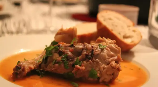 Un plat savoureux d'osso bucco, garni de persil frais, servi avec du pain croustillant. Un délice pour accompagner quel vin avec osso bucco.