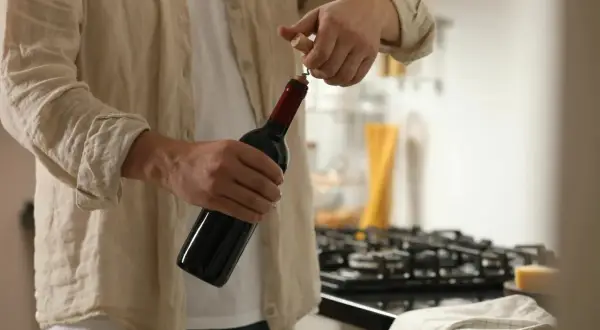 Un homme ouvre une bouteille de vin rouge. Il est temps de conservation rosé ouvert, mais ce vin rouge est prêt à être dégusté.