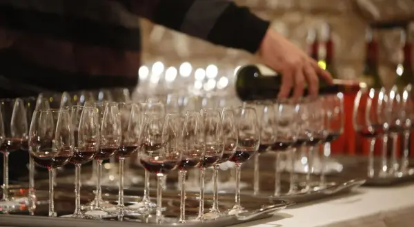 Dégustation de vin rouge, une main verse le liquide dans des verres. Une occasion spéciale pour savourer un premier grand cru.