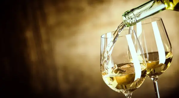 Un vin blanc sucré est versé dans un verre, créant une ambiance chaleureuse et invitante.