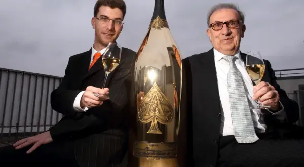 Deux hommes en costume célèbrent avec une gigantesque bouteille de champagne dorée, une véritable bouteille Midas.
