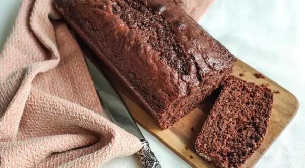 Un délicieux gâteau yaourt chocolat, moelleux et intense, prêt à être dégusté. Une tranche coupée révèle sa texture aérée.