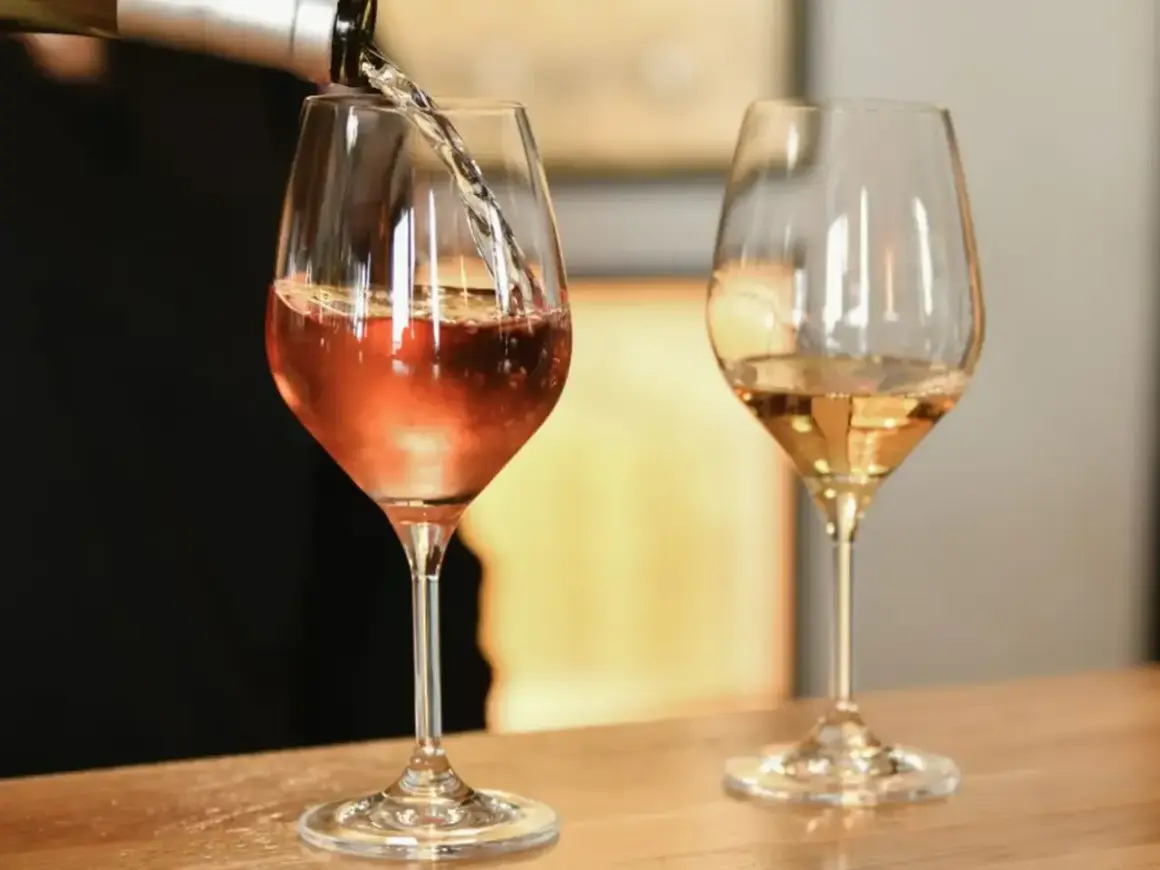 Un verre de vin blanc bouchonné, d'une couleur rosée, est servi dans un verre. Un autre verre de vin blanc est à côté.