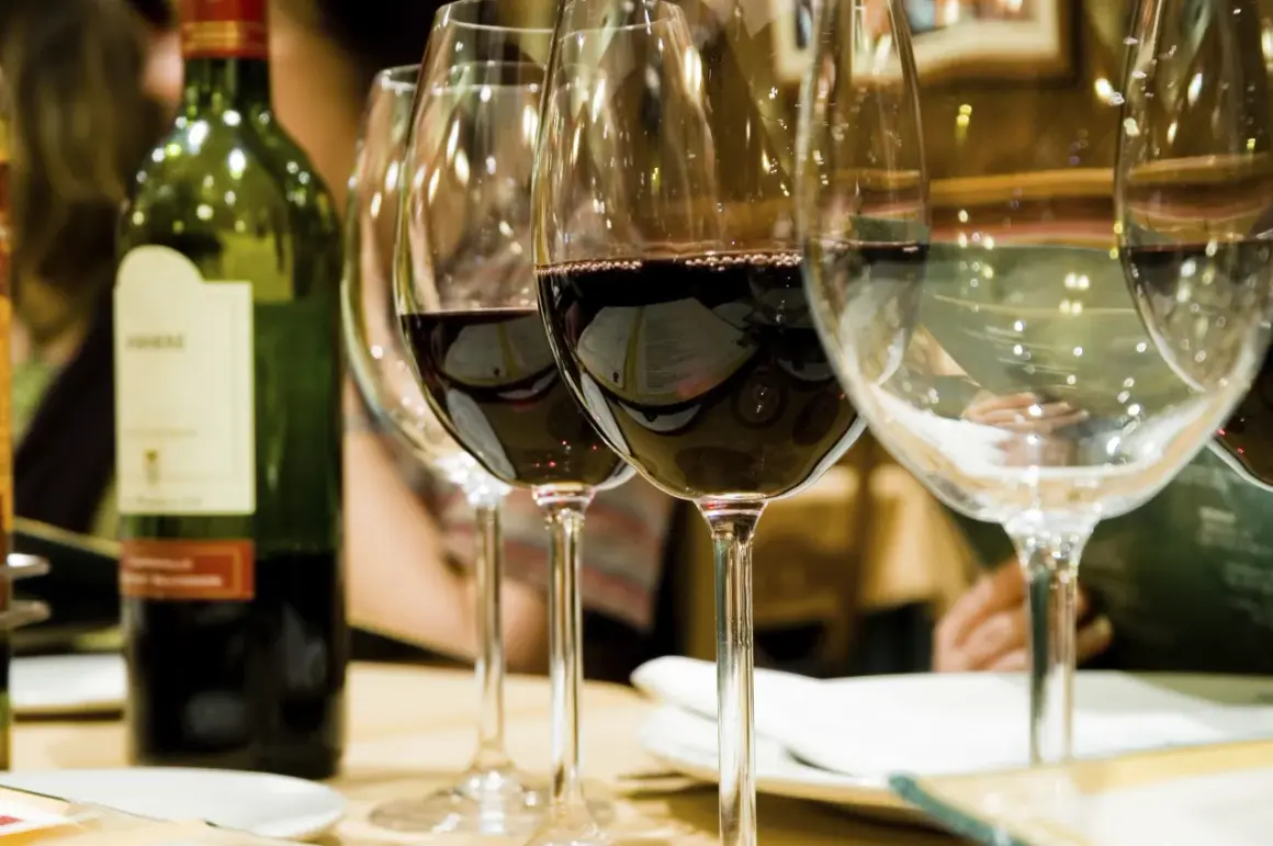 Une bouteille de vin rouge et plusieurs verres remplis de vin à la belle couleur rubis.