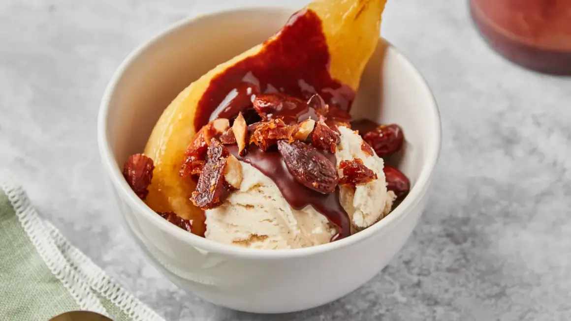 Poire pochée, glace vanille, sauce chocolat et amandes effilées pour une poire Belle Hélène gourmande.