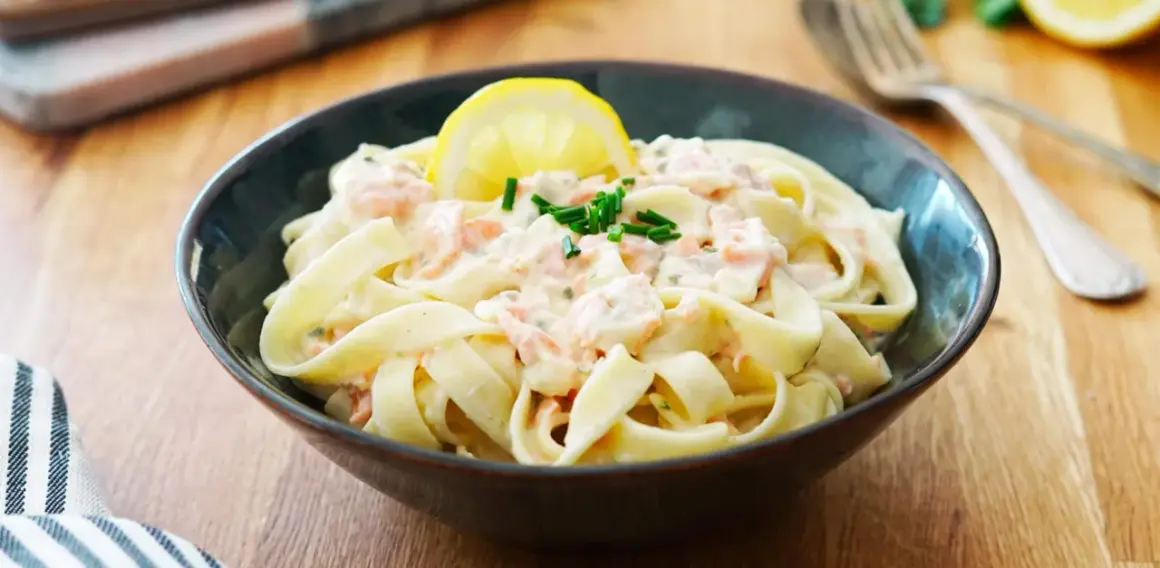 Un plat de tagliatelles au saumon crémeuses, garni d'une tranche de citron et de ciboulette fraîche. Un délice pour les papilles.