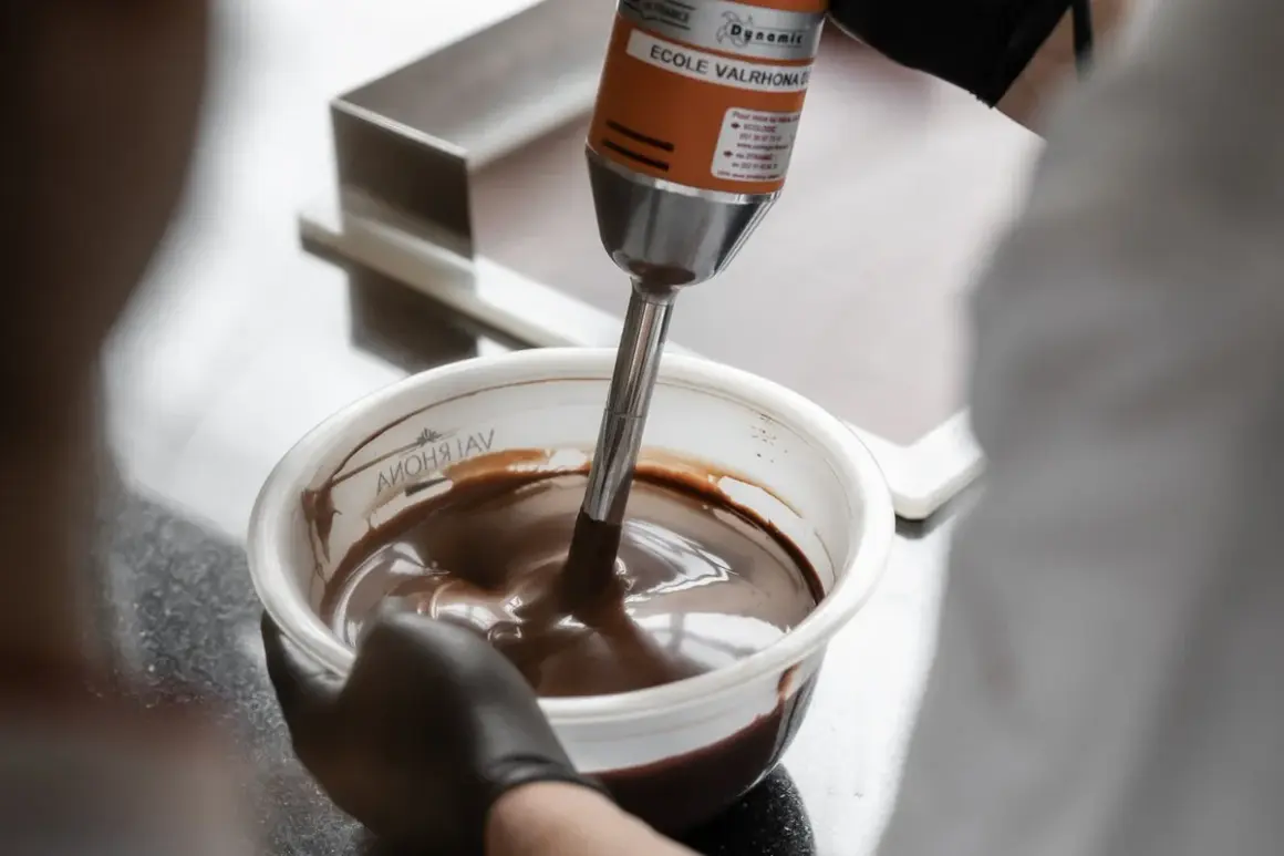 Un mixeur plongeant prépare une onctueuse ganache chocolat dans un bol.
