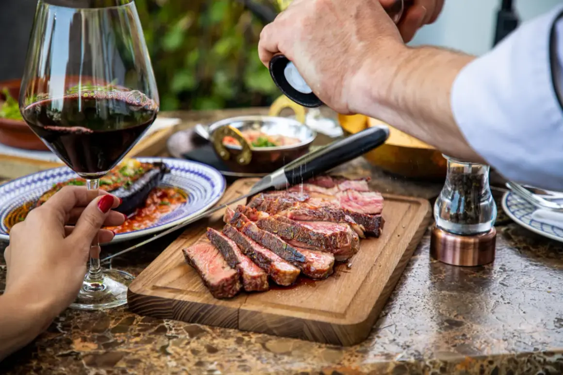 Un délicieux steak de vin rouge barbecue est assaisonné de poivre fraîchement moulu, prêt à être dégusté avec un verre de vin rouge.