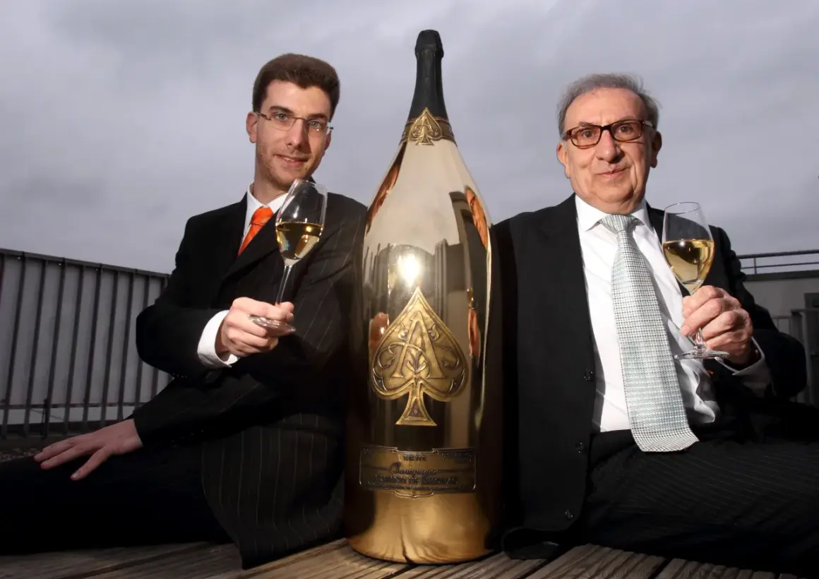 Deux hommes en costume célèbrent avec une gigantesque bouteille de champagne dorée, une véritable bouteille Midas.