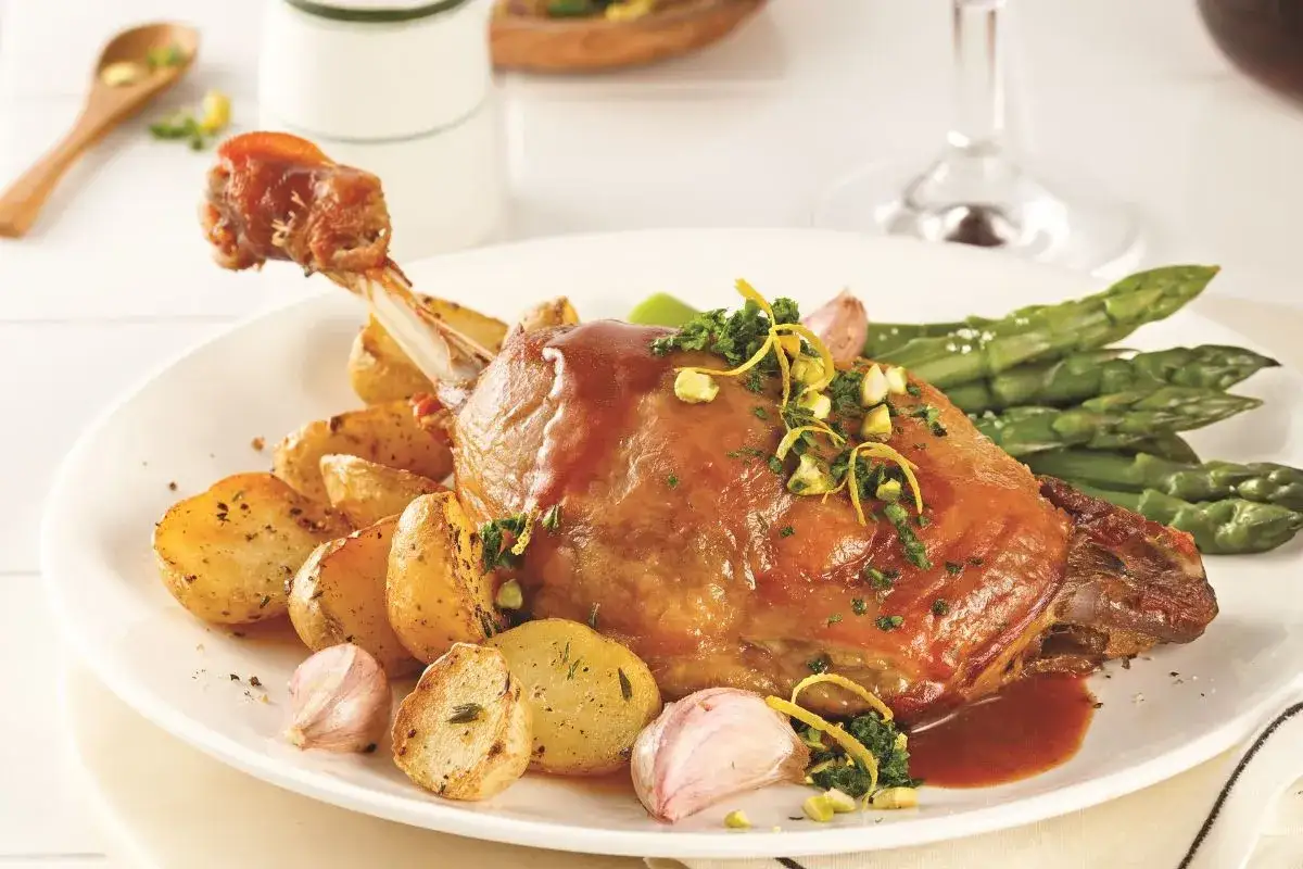 Un plat gourmand : une cuisse de canard confite, accompagn&eacute;e de pommes de terre r&ocirc;ties, d'asperges vertes et d'une sauce savoureuse. Un d&eacute;lice pour les amateurs de bon vin.