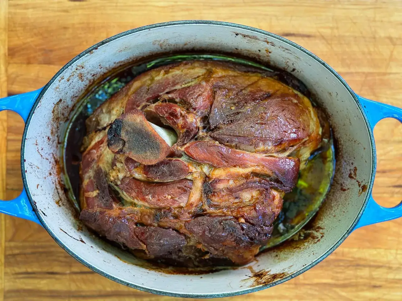 Gros morceau de porc r&ocirc;ti dans une cocotte bleue, pr&ecirc;t &agrave; &ecirc;tre effiloch&eacute;. La viande est dor&eacute;e et juteuse.