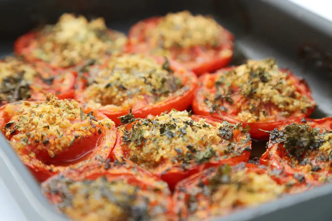 Tomates provençales gratinées, garnies d'herbes et de chapelure, dans un plat de cuisson.