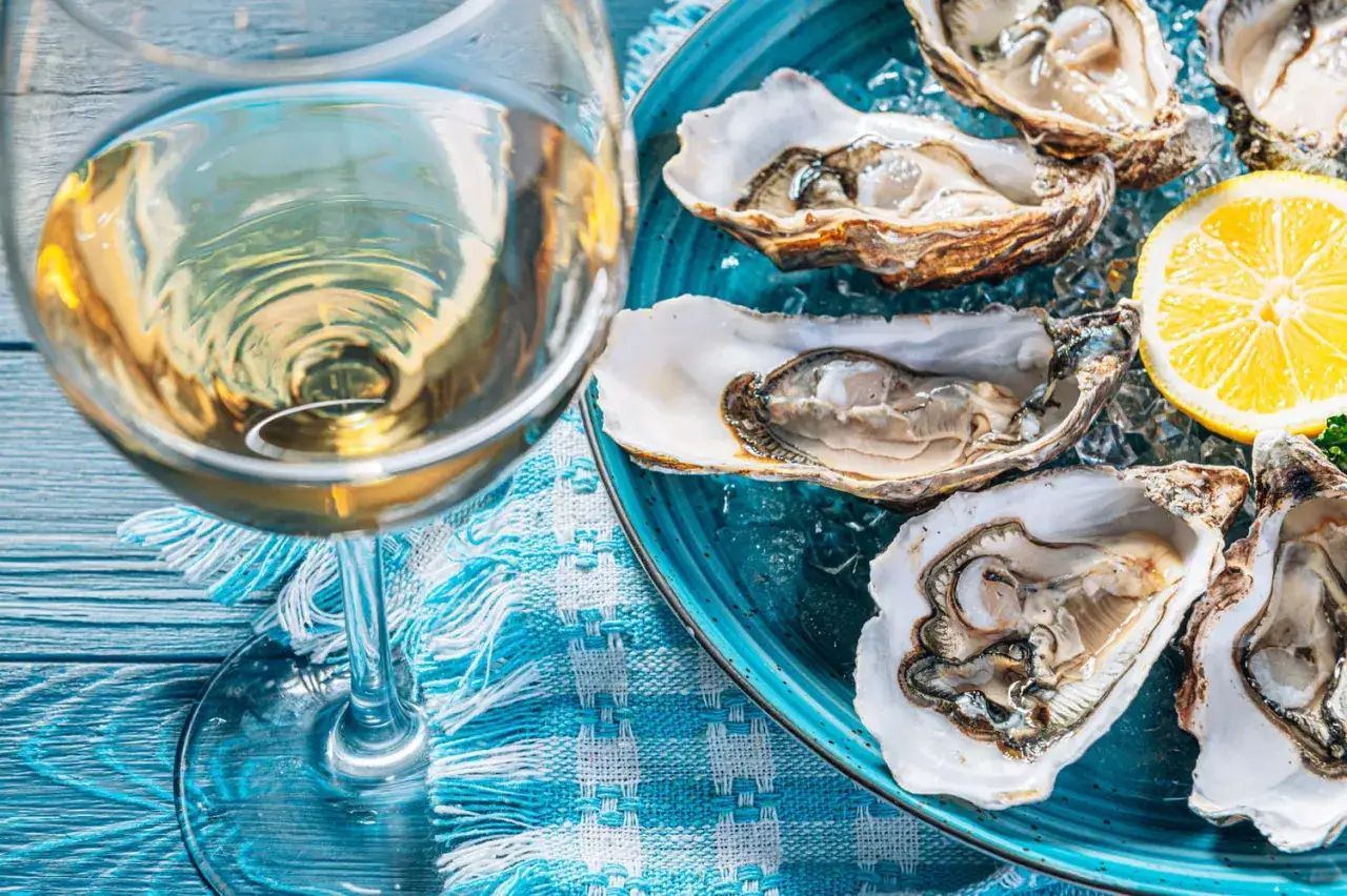 Un verre de vin blanc frais et des huîtres sur glace, un accord parfait pour un repas d'été. Quel vin blanc avec les huîtres ? Un Muscadet ou un Chablis serait idéal.