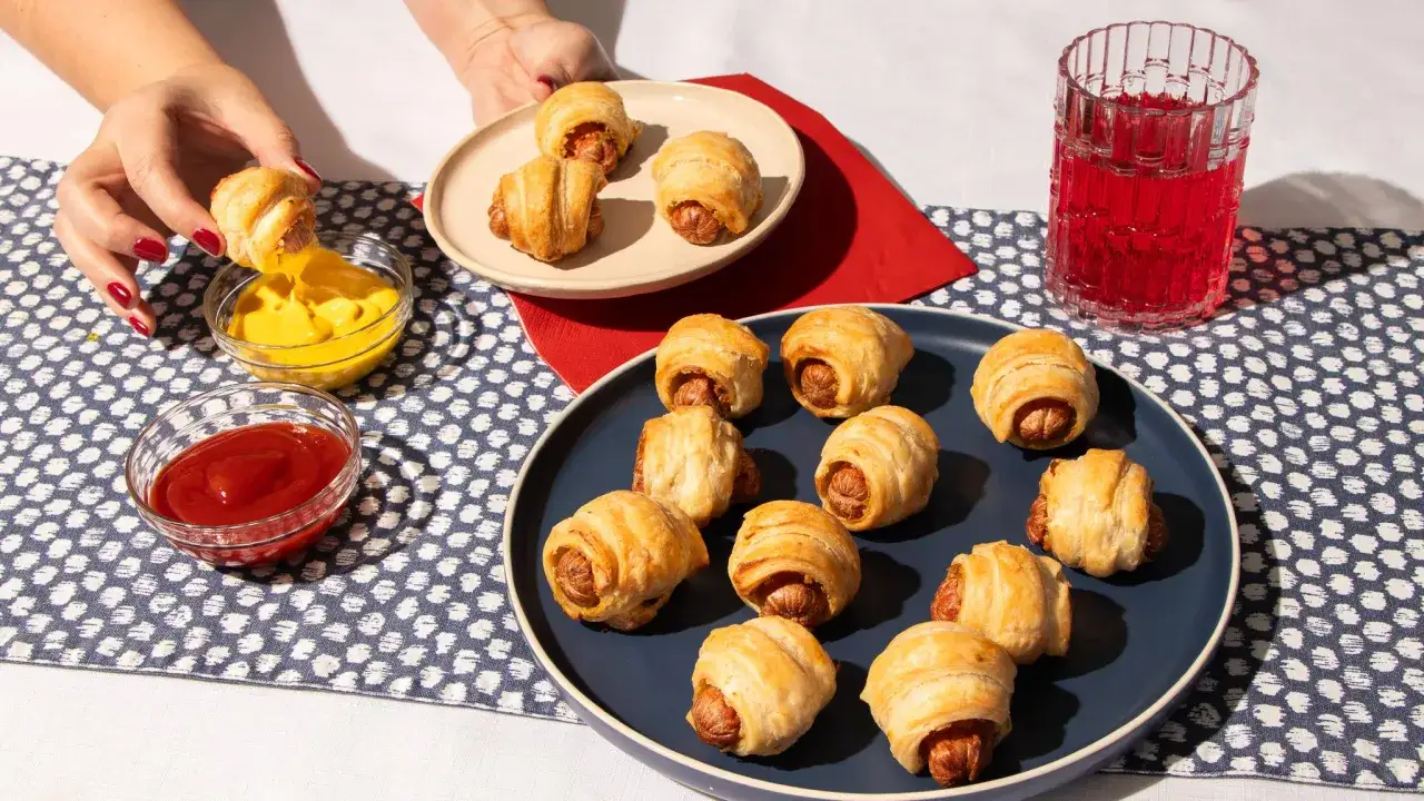 Des feuillet&eacute;s saucisse dor&eacute;s, certains tremp&eacute;s dans de la moutarde ou du ketchup, pr&ecirc;ts &agrave; &ecirc;tre d&eacute;gust&eacute;s.