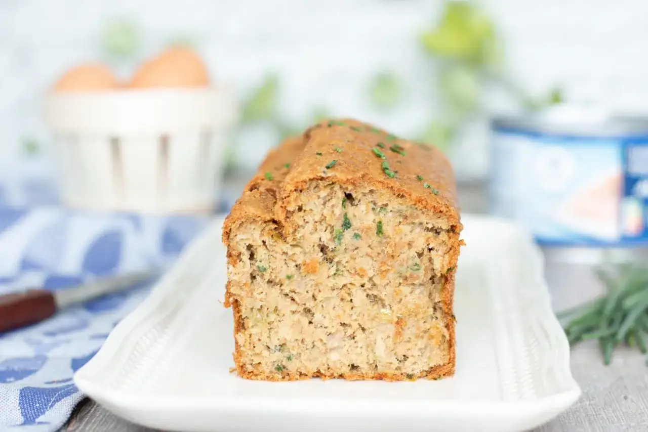 Un savoureux cake au thon, garni de ciboulette fraîche, prêt à être dégusté.