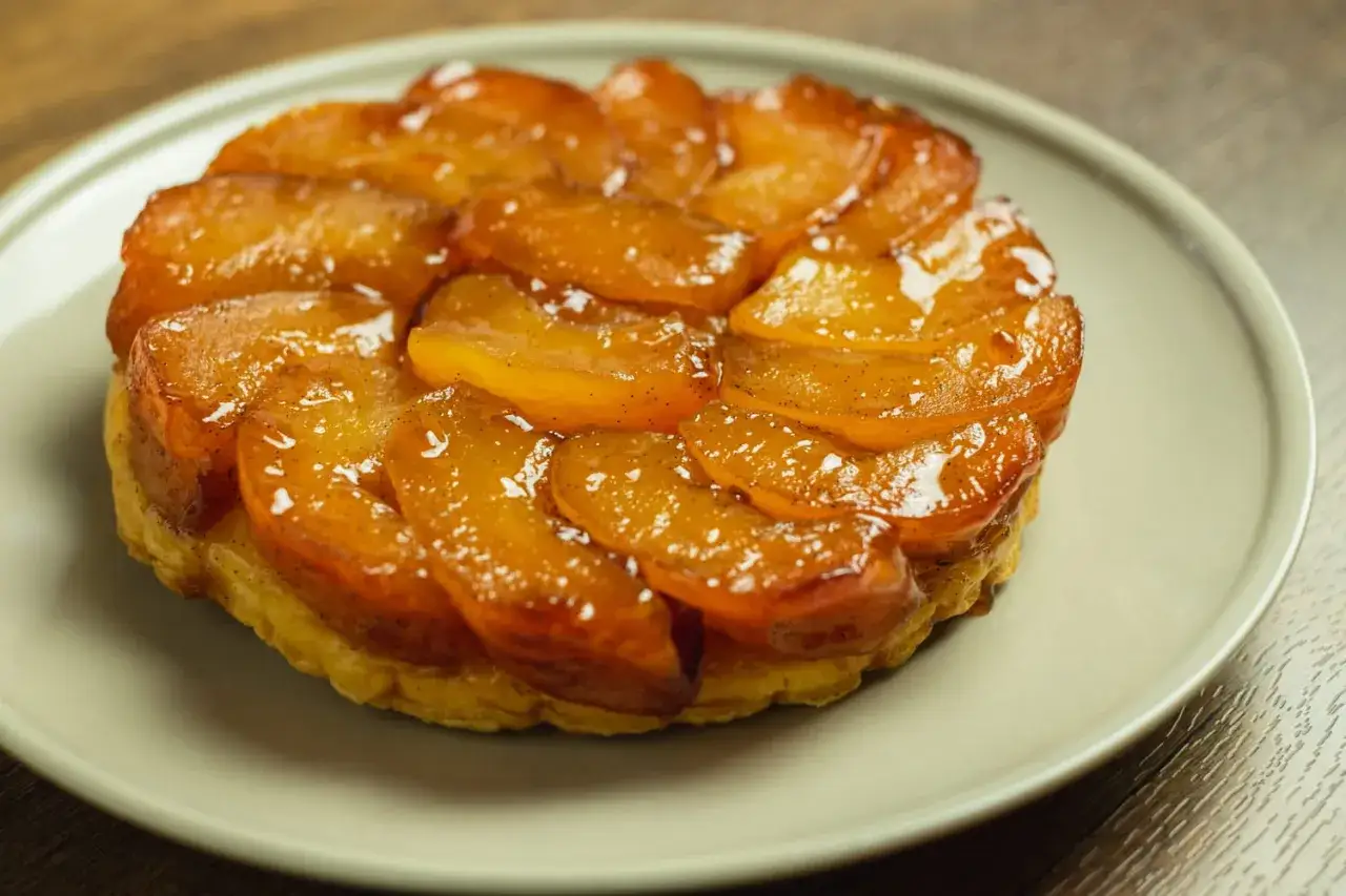 Une tarte tatin aux pommes caramélisées, dorée et brillante, prête à être dégustée.