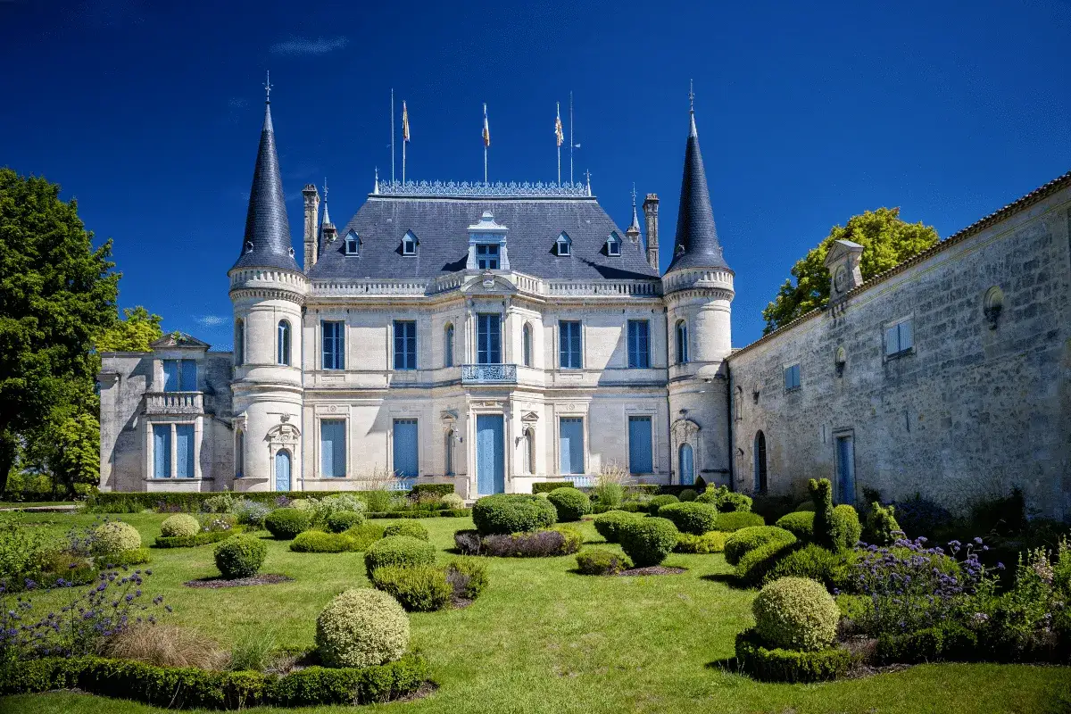 Magnifique ch&acirc;teau, un joyau de la liste domaine viticole bordeaux, avec son jardin &agrave; la fran&ccedil;aise et ses tours &eacute;lanc&eacute;es sous un ciel bleu &eacute;clatant.
