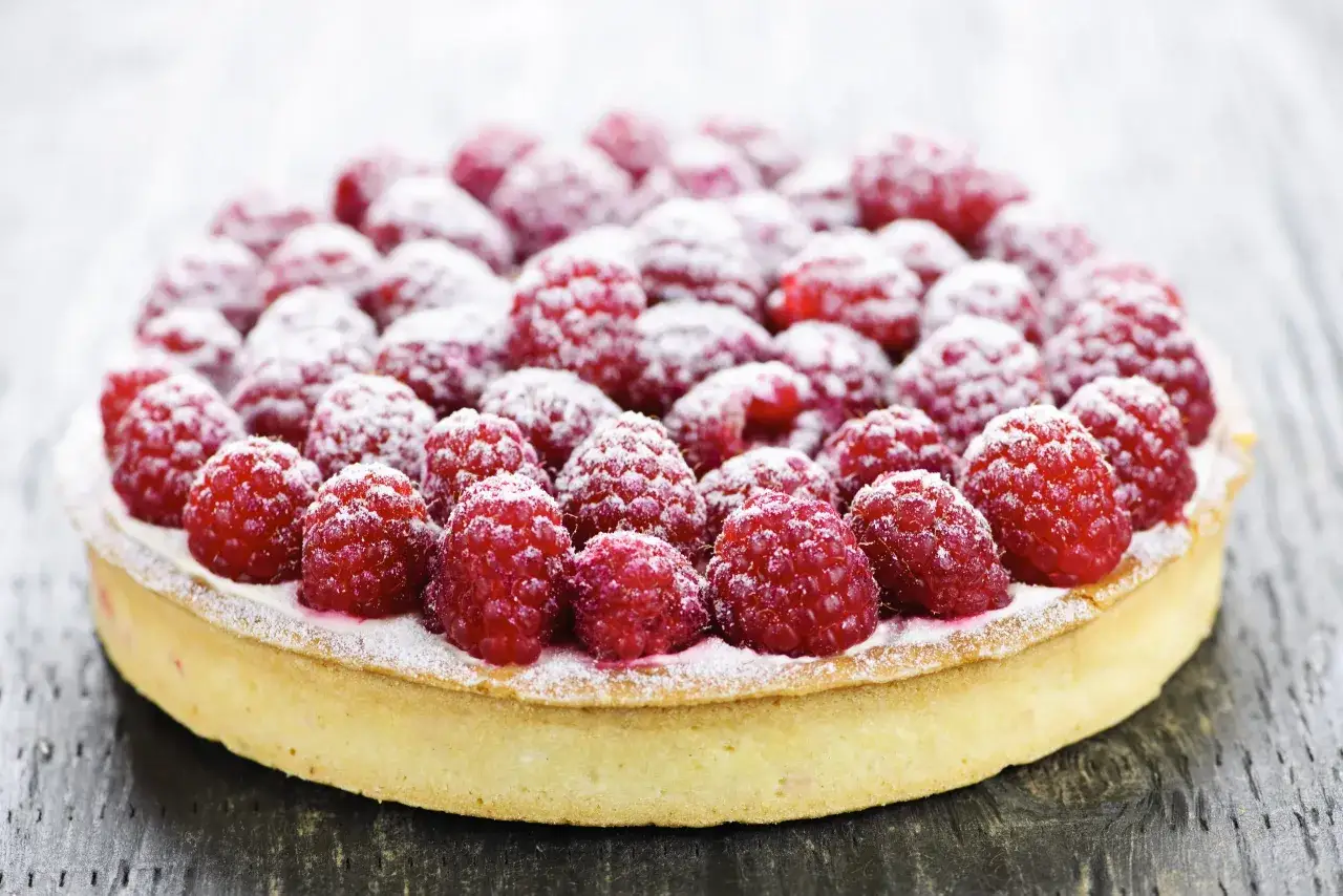 Tarte aux framboises, recouverte de sucre glace, pr&ecirc;te &agrave; &ecirc;tre d&eacute;gust&eacute;e.