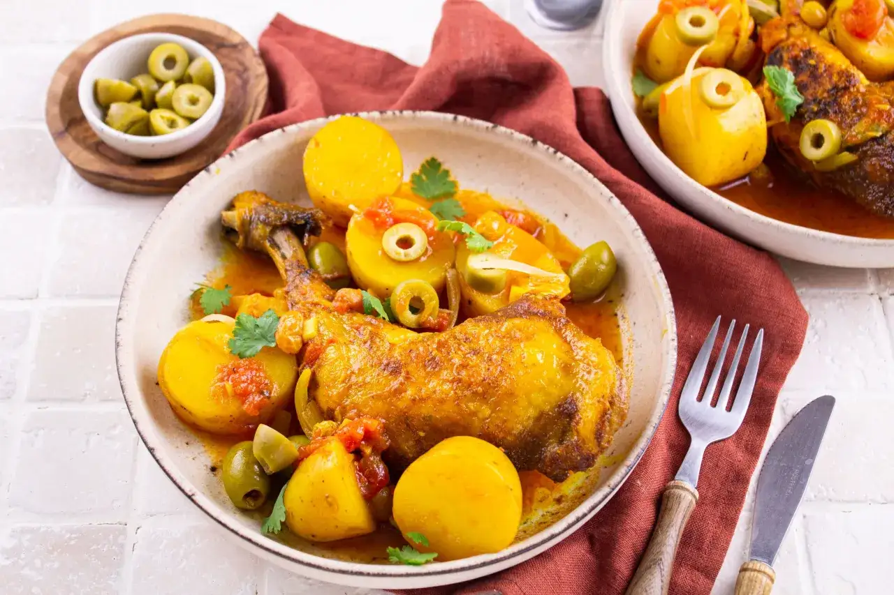 Un plat appétissant de poulet aux olives, garni de pommes de terre et de persil frais, prêt à être dégusté.