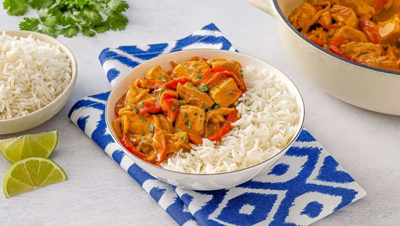 Un délicieux poulet curry coco crémeux, servi avec du riz basmati et des quartiers de citron vert.
