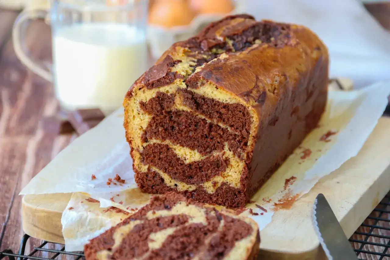 Un d&eacute;licieux g&acirc;teau marbr&eacute;, coup&eacute; en tranches, avec un verre de lait et des &oelig;ufs en arri&egrave;re-plan.