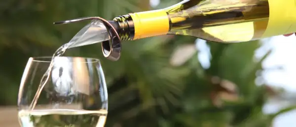 Un vin blanc est versé dans un verre, suggérant le plaisir d'un bon vieillissement du vin.