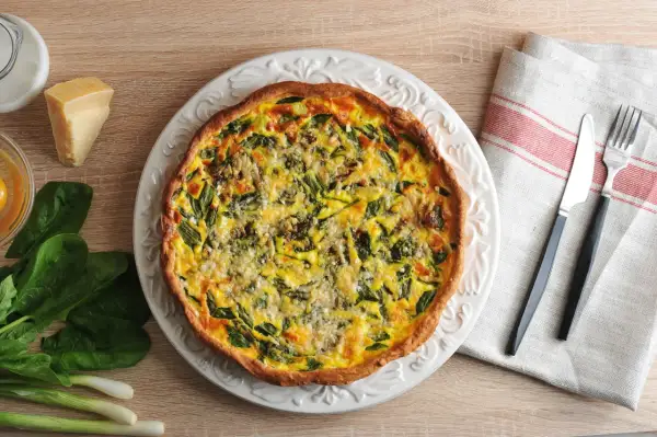 Une appétissante quiche aux légumes, garnie d'épinards et de fromage, prête à être dégustée.