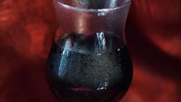 Verre de vin rouge givré, fraîchement sorti du frigo. Les gouttelettes d'eau perlent sur le verre, promettant une dégustation rafraîchissante.