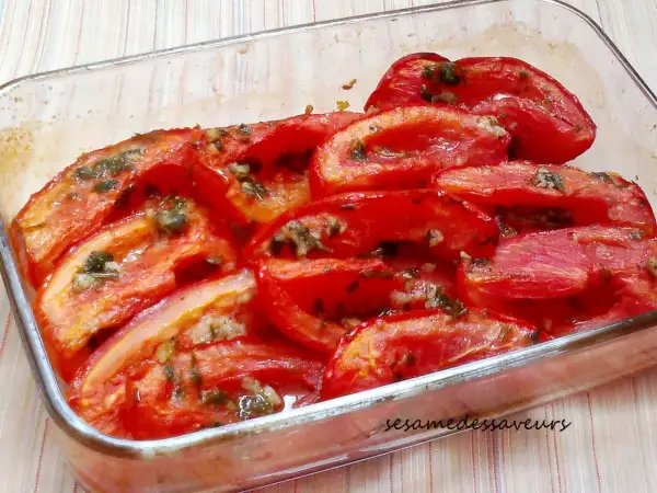 Tomates au four coupées en quartiers, baignant dans leur jus avec des herbes et de l'ail. Un plat simple et savoureux.