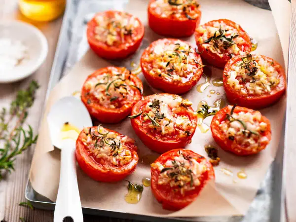 Tomates provençales garnies d'herbes et de fromage, rôties sur une plaque. Un délice méditerranéen.