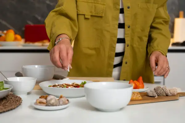 Une personne prépare une salade. Si vous cherchez par quoi remplacer du vin blanc dans une recette, pensez à des ingrédients frais et savoureux comme ceux présentés.