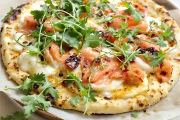 Une délicieuse pizza saumon, garnie de fromage fondant et de coriandre fraîche. Un vrai régal pour les yeux et les papilles !