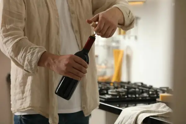 Un homme ouvre une bouteille de vin rouge. Il est temps de conservation rosé ouvert, mais ce vin rouge est prêt à être dégusté.