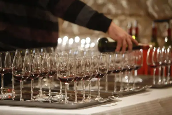 Dégustation de vin rouge, une main verse le liquide dans des verres. Une occasion spéciale pour savourer un premier grand cru.