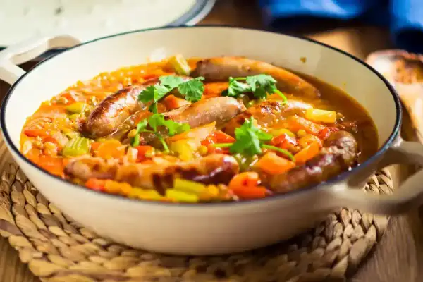 Un plat réconfortant de saucisses et lentilles mijotées avec des légumes, garni de coriandre fraîche. Un délice pour les papilles.